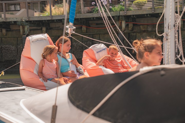 Children relaxing on bean bags aboard a sailboat.